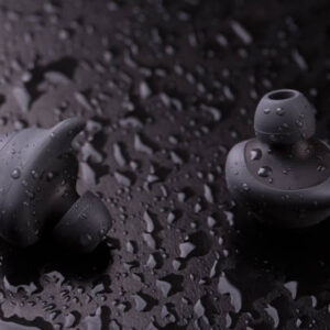 Intra-channel Bluetooth headphones on a dark background with water drops.